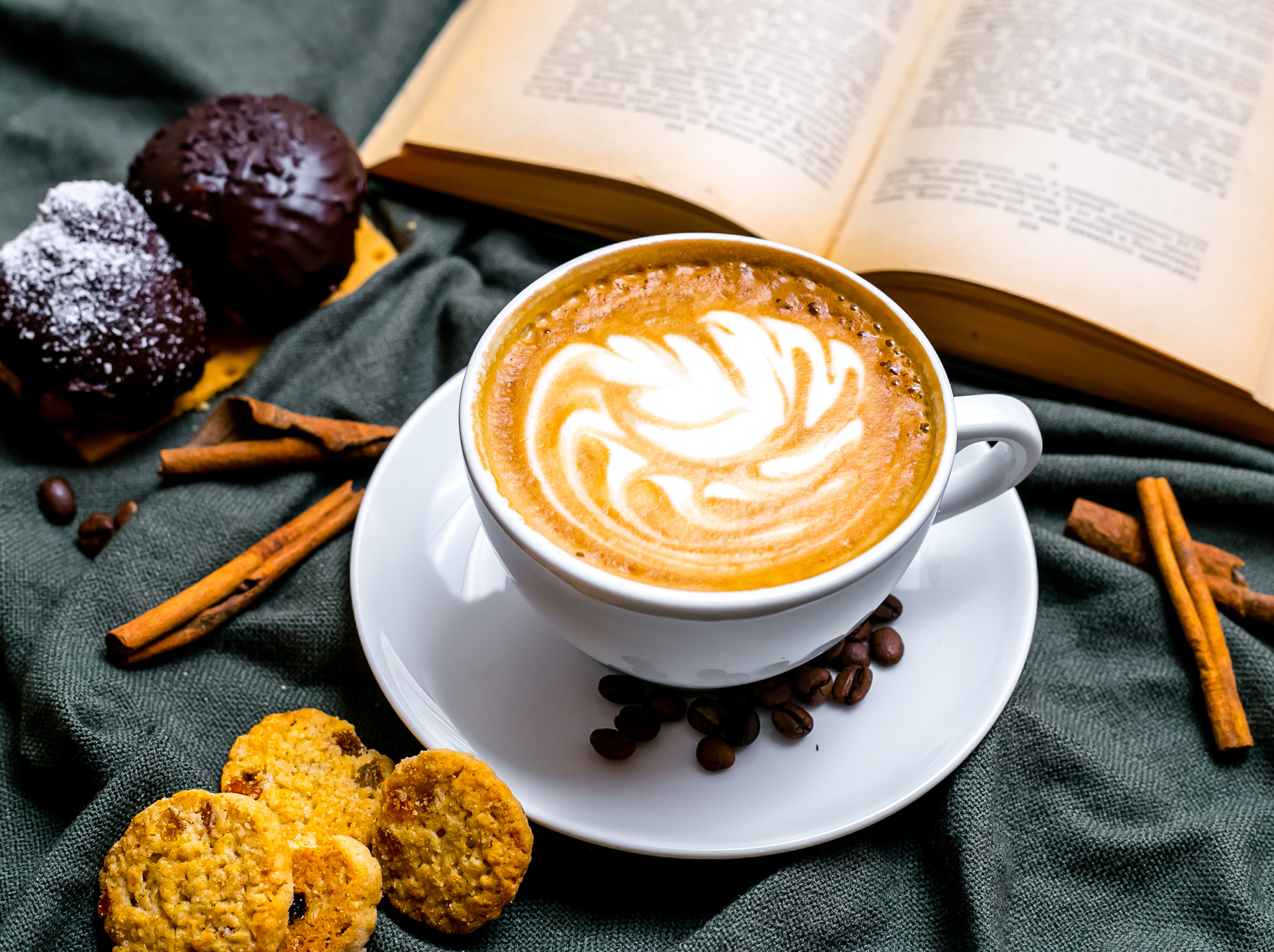 top view cup of cappuccino with chocolate cookies and raisin cookies and with a book on the table